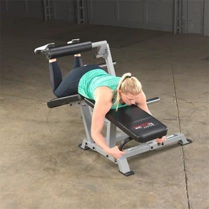 machine de musculation noire et grise femme en débardeur gris sur son ventre fait un exercice