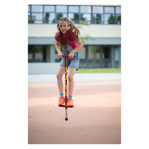 Enfant jouant sur un bâton sauteur Pogo Stick de couleur rouge